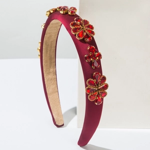 Détail d'un serre-tête baroque en velours rouge avec fleurs dorées et gemmes rubis