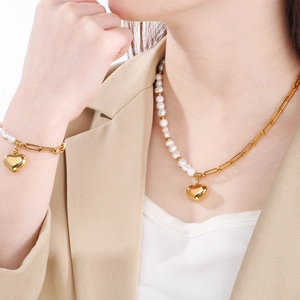 Vue détaillée du collier en perles et chaîne dorée avec pendentif cœur sur modèle