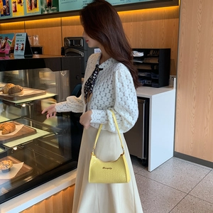 Minimalist yellow crocodile pattern underarm bag shown on a model in a cafe setting