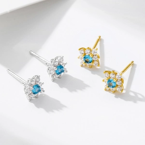 Elegant flower stud earrings with blue zircon center and pavé crystal petals in gold and silver