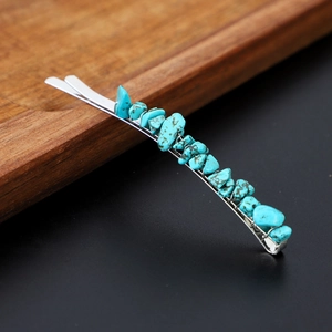Detail view of turquoise natural stone hair clip on rustic wood and dark background