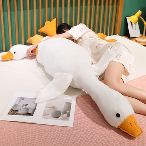 Close-up of soft white goose plush pillow held by a person on a cozy bed