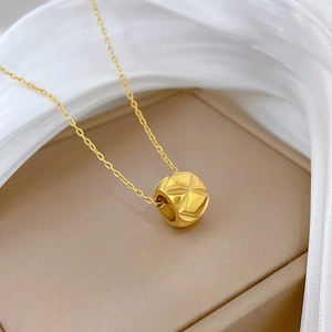 Macro shot of gold-plated waist-shaped cylinder pendant on titanium steel necklace