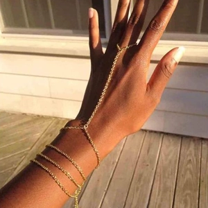 Detail of a gold-plated slave bracelet featuring multi-layer chains and finger ring linkage