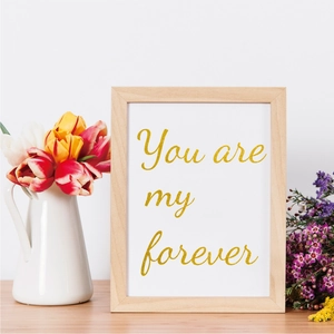 Detail of wooden picture frame with gold text and decorative flowers in a home setting