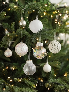 Detail of assorted white and transparent Christmas balls with textures on a lit pine tree