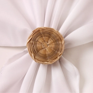 Close-up of handmade round rattan napkin ring on a white linen napkin with natural texture