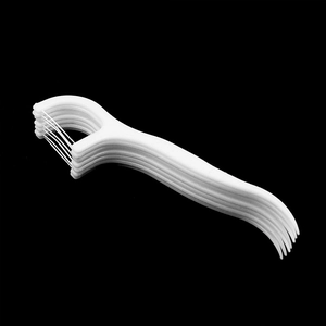 Macro shot of white plastic dental floss picks stacked on a black background