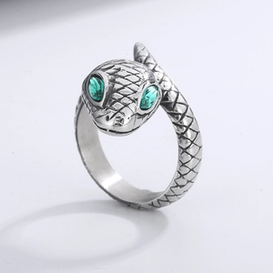 Macro detail of silver snake ring with green gem eyes and textured scale engraving
