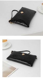 Detail view of black glossy crocodile-embossed clutch bag with sparkling rhinestone hardware