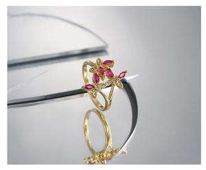Macro shot of gold butterfly ring featuring marquise-cut red stones and fine diamonds