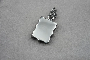 Close-up of square silver steel pendant with white stone inlay on fabric background