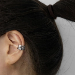 Macro detail of silver stainless steel clip-on earrings on model's ear cartilage