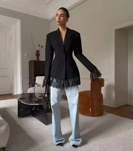 Detail of elegant black blazer with lace hem and cuffs paired with light blue jeans