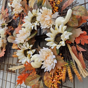 Autumn wreath with white sunflowers, pumpkins, maple leaves, and berries on vine base