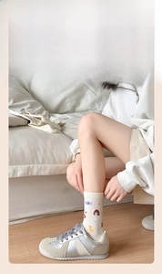 Détail de chaussettes mi-mollet blanc cassé avec motifs de fille et baskets argentées