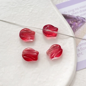 Macro detail of red gradient tulip glass beads for DIY jewelry making on white tray