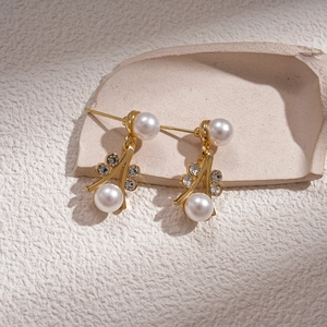 Detailed view of elegant gold branch earrings with white imitation pearls and rhinestones