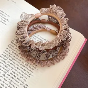 Lot de trois chouchous en dentelle aux tons café posés sur un livre vintage