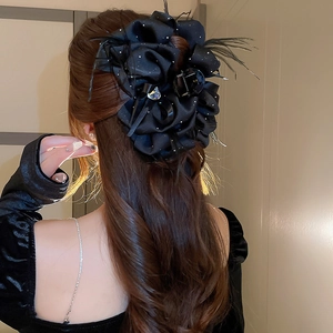 Détail d'une grande pince à cheveux rose en satin noir avec cristal cœur et plumes