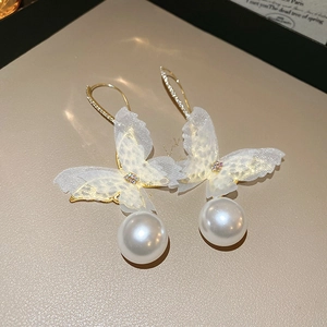 Detail of gold butterfly pearl earrings featuring delicate mesh wings and rhinestones