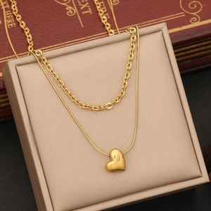 Detailed view of layered gold heart necklace set on a beige jewelry box display