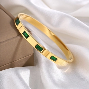 Detailed shot of 18K gold-plated titanium bangle with five emerald green zircon stones