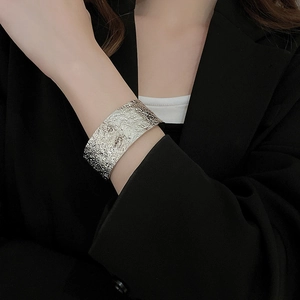 Detail showing high-gloss silver wide cuff bracelet with lava textured finish on a model