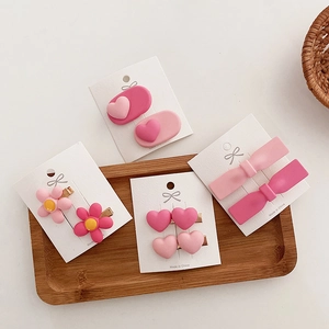 Detail of pink resin hair clip set featuring 3D heart, flower, and bow designs