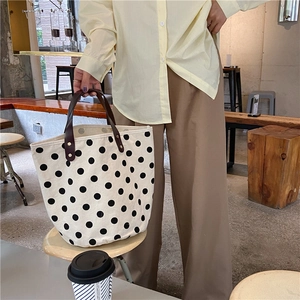 Detailed shot of a polka dot canvas tote bag with brown handles in a cozy cafe setting