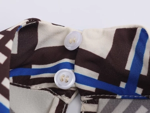 Detailed view of high neck collar with geometric print and white button closures