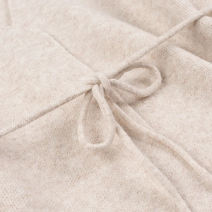 Close-up of knit cardigan detail featuring a neat oatmeal bow tie closure and soft texture