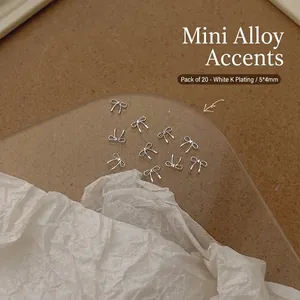 Detail of 20pcs 5x4mm silver alloy bowknot nail charms on a round display tray