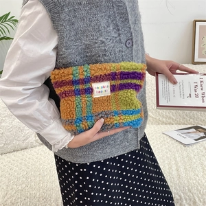 Detailed view of the colorful checkered plush cosmetic bag held in hand for travel