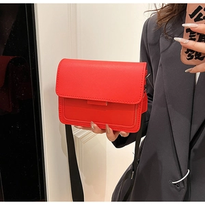 Detail of red rectangular crossbody bag with wide black strap and silver hardware