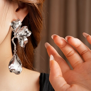 Close-up of a large silver metal flower petal earring worn by a model showing fine detail