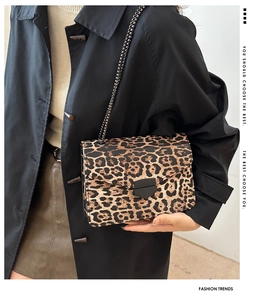 Detailed view of leopard print crossbody bag with black metal chain and flap closure
