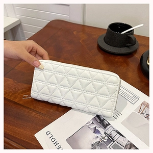 Close-up of white long quilted wallet with diamond stitching on dark wooden surface