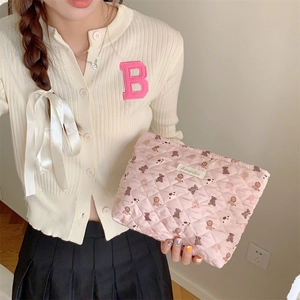 Close-up of pink quilted cosmetic bag with cute cartoon bear prints held by a model