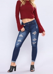 Vue détaillée du jean skinny bleu foncé avec des déchirures aux genoux et moustaches