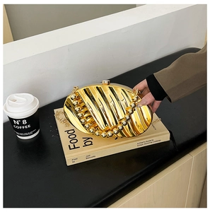Detail of gold evening clutch bag with shell leaf texture and elegant ball chain trim