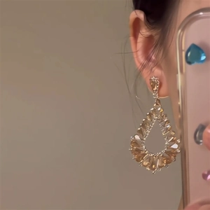 Vue détaillée de boucles d'oreilles en cristal ambre avec motif goutte d'eau ajouré