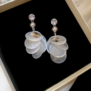 Close-up of zircon earrings with shell tassels and crystals on a black velvet box