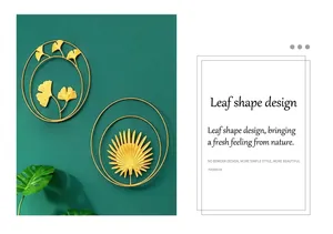 Detail of gold metal ginkgo and palm leaf wall art on a textured dark green background