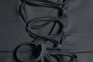 Détail de la robe noire avec un design de corset à lacets et un tissu en maille épais