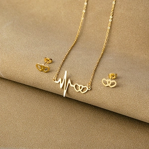 Detailed macro view of gold heartbeat and double heart necklace with matching earrings