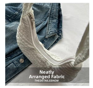 Close-up of white pleated cloud bag showing smooth metal zipper and quilted texture