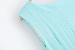 Détail macro d'une robe midi asymétrique montrant la texture du lin bleu clair et la couture