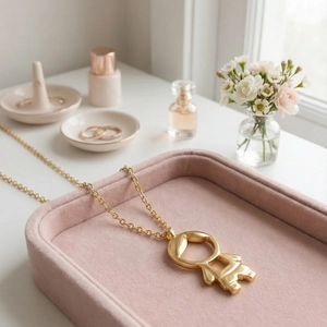 Détail macro du pendentif garçon doré sur chaîne à maillons avec plateau en velours rose