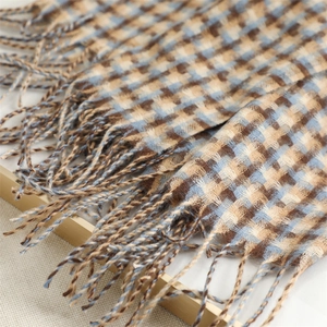 Detail of blue and brown plaid scarf featuring soft cashmere-feel fabric and twisted tassels